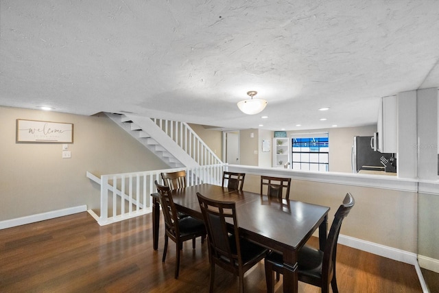 dining space featuring a textured ceiling and dark wood-type flooring