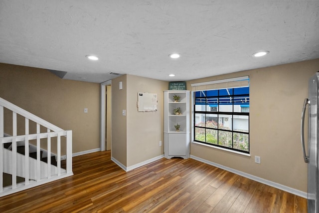 spare room with dark hardwood / wood-style floors and a textured ceiling