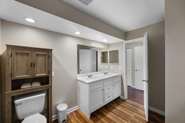 bathroom featuring hardwood / wood-style flooring, dual bowl vanity, and toilet