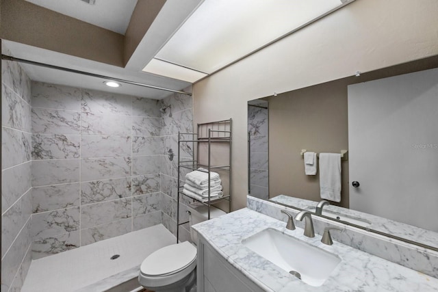 bathroom featuring toilet, vanity, and a tile shower