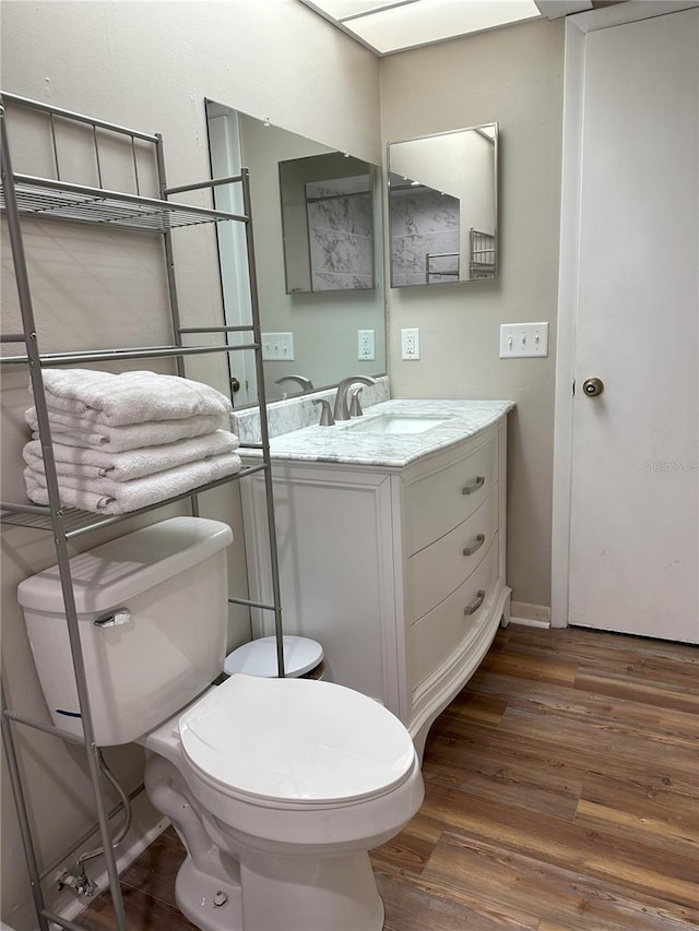 bathroom featuring wood-type flooring, vanity, and toilet