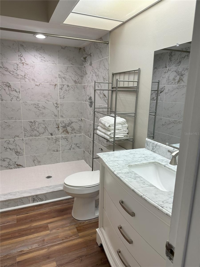 bathroom with oversized vanity, tiled shower, toilet, and hardwood / wood-style flooring