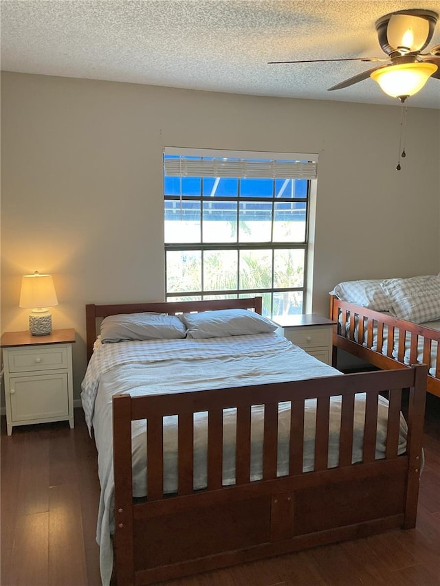 bedroom featuring ceiling fan, dark wood-type flooring, and a textured ceiling