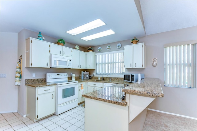 kitchen featuring light stone counters, white cabinets, sink, white appliances, and kitchen peninsula