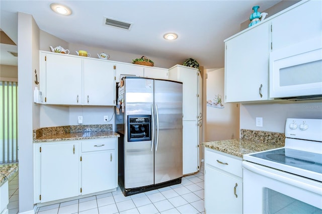 kitchen with white appliances, light tile floors, and white cabinetry