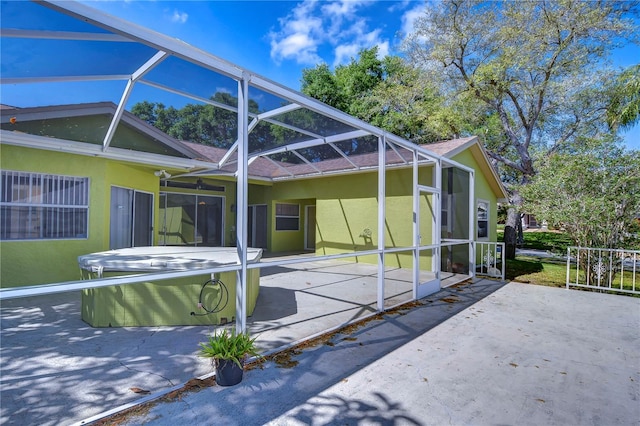 exterior space with a hot tub, a patio area, and glass enclosure