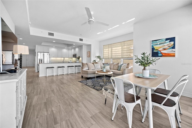 dining space featuring sink, ceiling fan, and light hardwood / wood-style floors