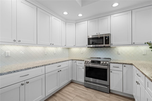 kitchen featuring tasteful backsplash, stainless steel appliances, white cabinetry, and light stone countertops