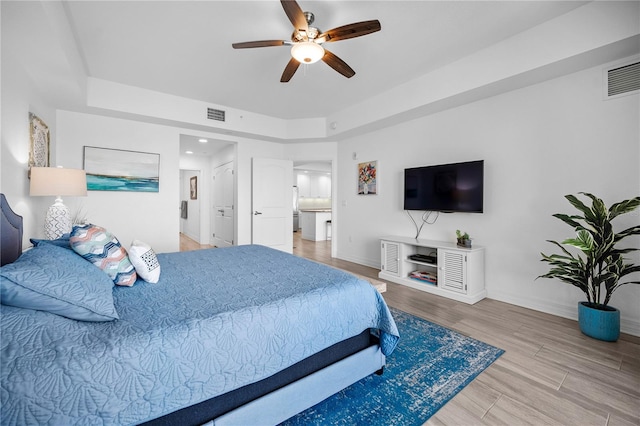 bedroom with ceiling fan, hardwood / wood-style flooring, and connected bathroom