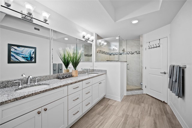 bathroom featuring double vanity and a shower with shower door