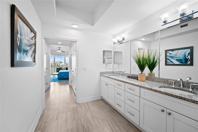 bathroom featuring a raised ceiling, ceiling fan, and double vanity