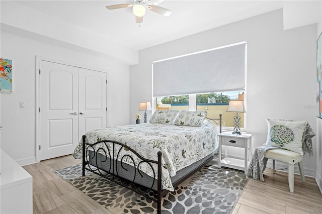 bedroom with a closet, light hardwood / wood-style flooring, and ceiling fan