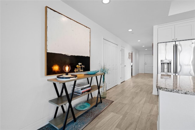 kitchen with high end fridge, light hardwood / wood-style floors, white cabinets, and light stone counters