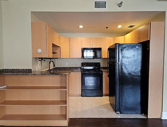 kitchen featuring light brown cabinets, kitchen peninsula, black appliances, dark stone counters, and light tile floors