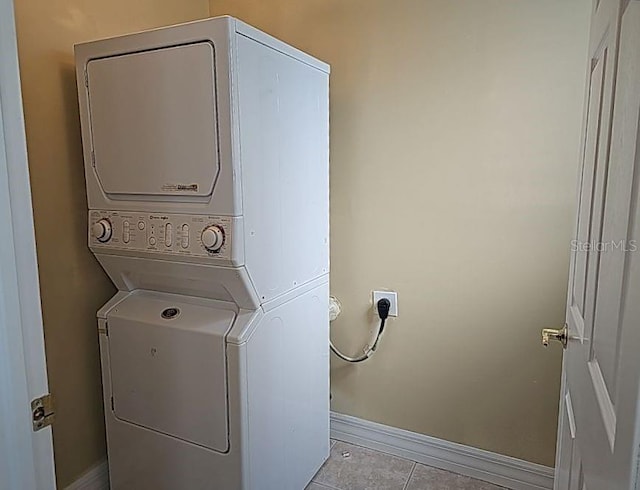 laundry room with stacked washer / dryer, hookup for an electric dryer, and light tile flooring