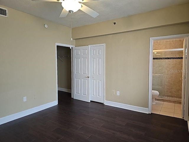 unfurnished bedroom featuring ceiling fan, ensuite bathroom, and dark hardwood / wood-style floors