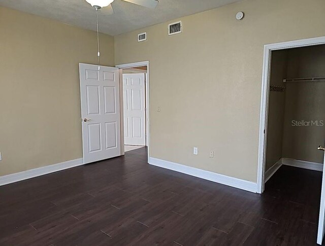 unfurnished bedroom with a closet, dark hardwood / wood-style floors, and ceiling fan