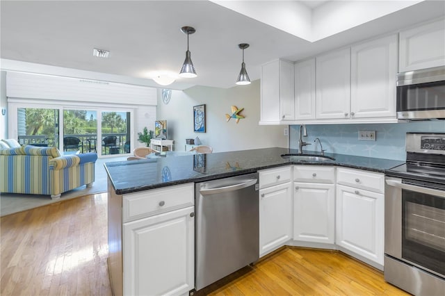 kitchen featuring white cabinets, appliances with stainless steel finishes, sink, hanging light fixtures, and kitchen peninsula