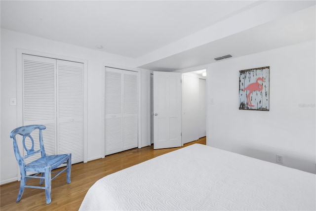 bedroom with wood-type flooring and multiple closets