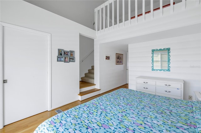 bedroom with a high ceiling and hardwood / wood-style flooring