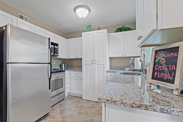 kitchen with light stone counters, stainless steel appliances, white cabinetry, and light tile flooring