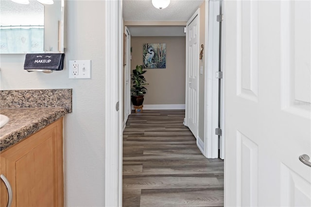 corridor with dark hardwood / wood-style floors and a textured ceiling