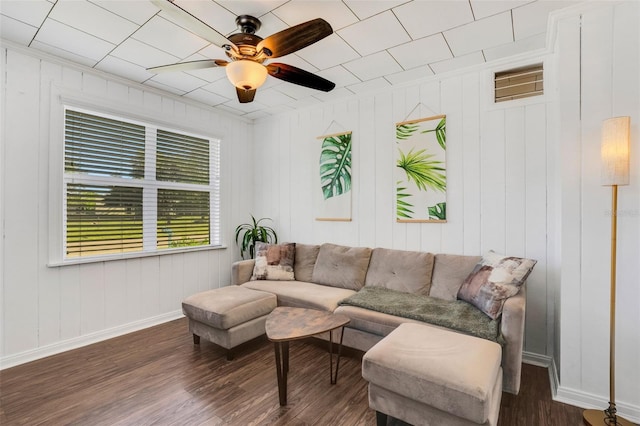 living room featuring ceiling fan, wood walls, and dark wood-type flooring