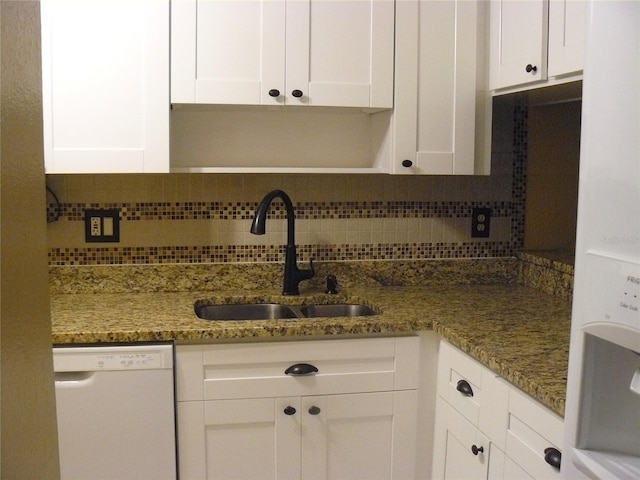 kitchen with tasteful backsplash, white cabinetry, sink, dark stone countertops, and white dishwasher