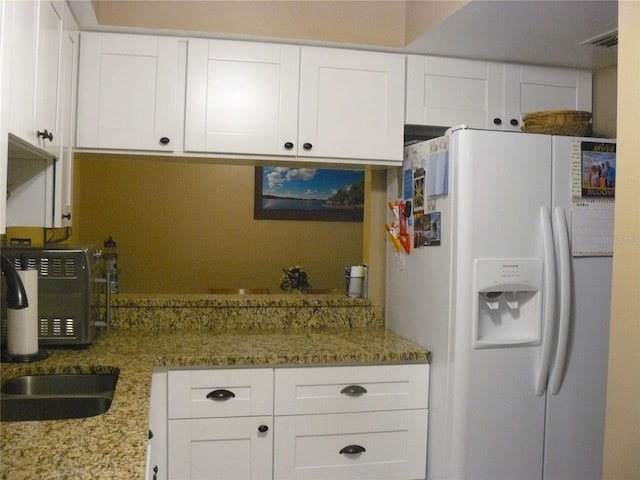 kitchen with sink, white refrigerator with ice dispenser, and white cabinets