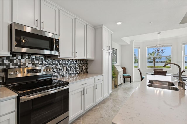 kitchen featuring pendant lighting, a sink, appliances with stainless steel finishes, white cabinets, and decorative backsplash