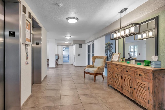 hall with elevator, light tile floors, and a textured ceiling