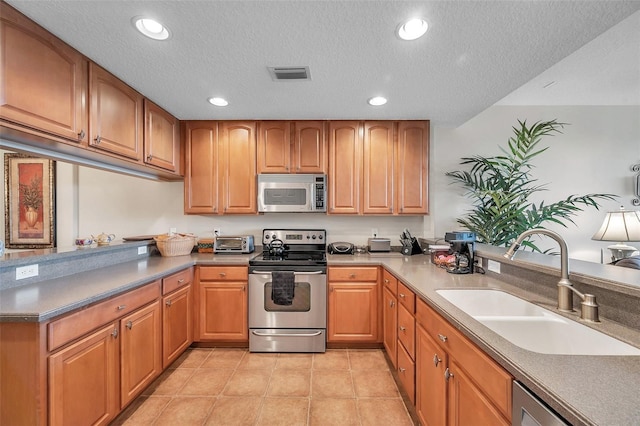 kitchen featuring sink, appliances with stainless steel finishes, a textured ceiling, and light tile floors