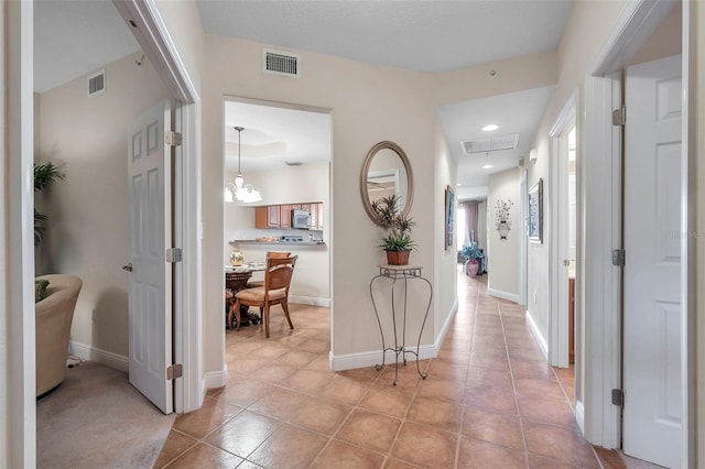 hall with a chandelier and light tile floors