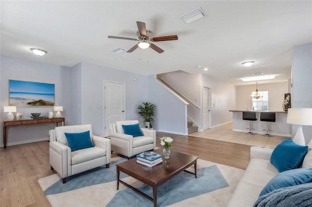 tiled living room featuring ceiling fan with notable chandelier