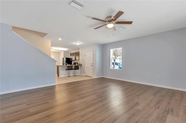 unfurnished living room featuring ceiling fan and light hardwood / wood-style flooring