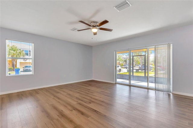 spare room with hardwood / wood-style flooring, a healthy amount of sunlight, and ceiling fan