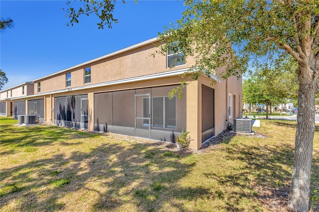 back of property featuring central air condition unit and a lawn