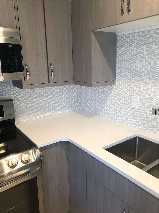 kitchen with tasteful backsplash, stainless steel appliances, light countertops, and modern cabinets