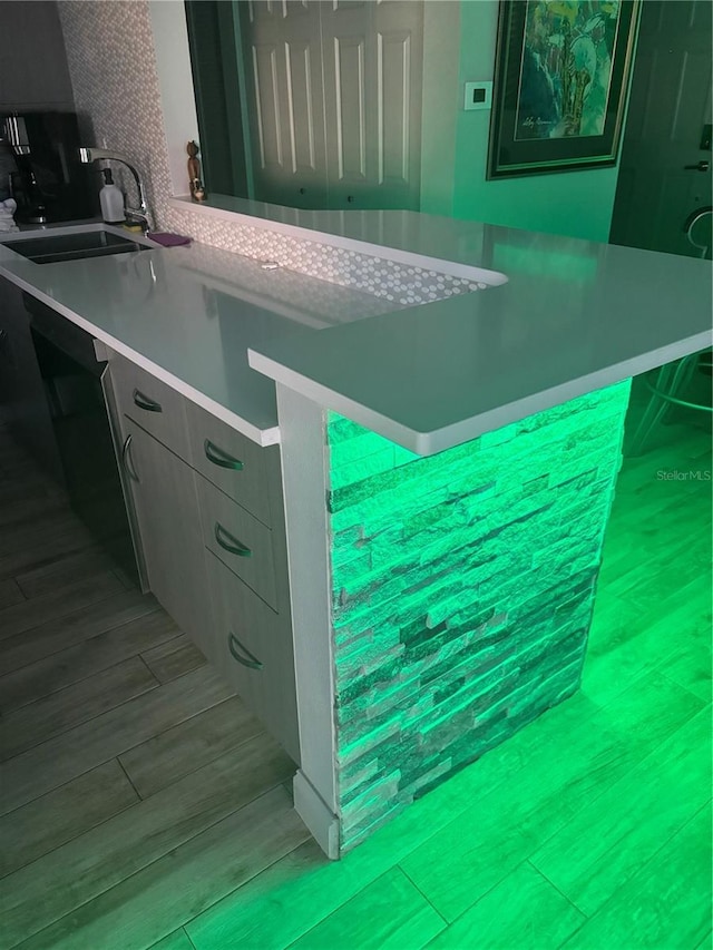 kitchen featuring light wood finished floors, backsplash, light countertops, and a sink