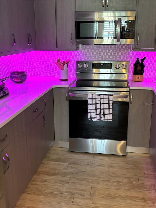 kitchen featuring backsplash, stainless steel appliances, and light wood-type flooring