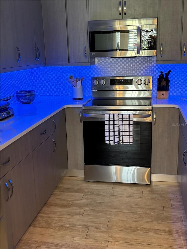 kitchen featuring light countertops, light wood-style floors, backsplash, and stainless steel appliances