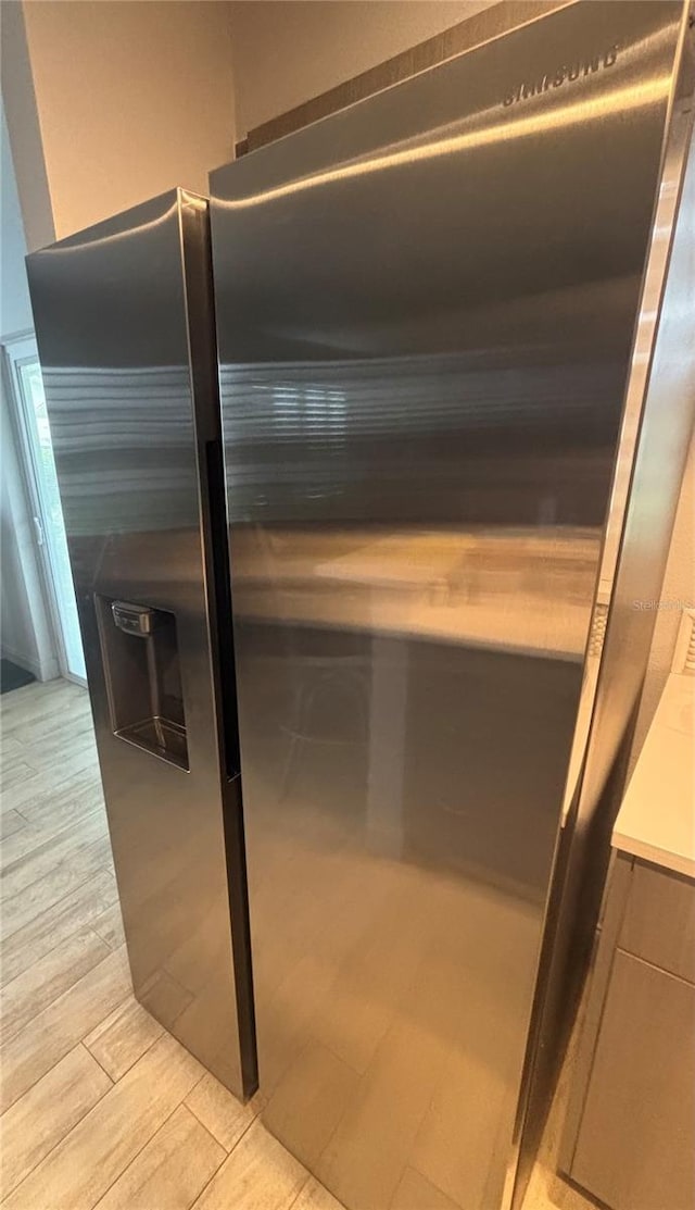 interior details featuring stainless steel fridge, light countertops, and light wood-style flooring