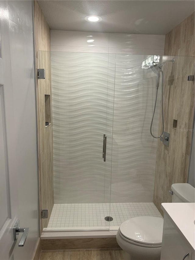 bathroom featuring vanity, a shower stall, and toilet