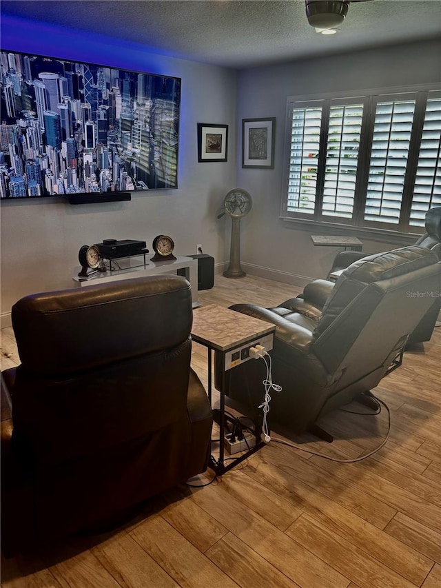 living room featuring wood finished floors, baseboards, and a textured ceiling