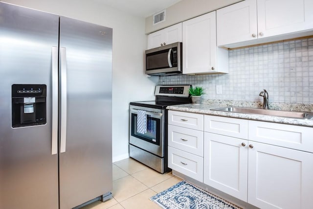 kitchen featuring sink, stainless steel appliances, tasteful backsplash, white cabinets, and light tile patterned flooring