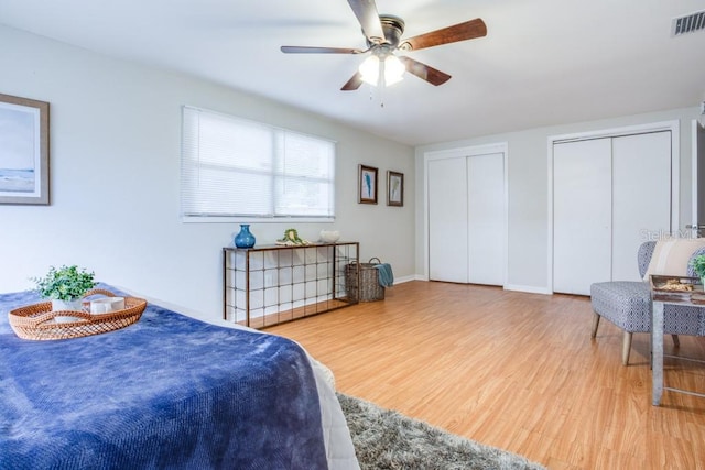 bedroom with multiple closets, ceiling fan, and light hardwood / wood-style flooring