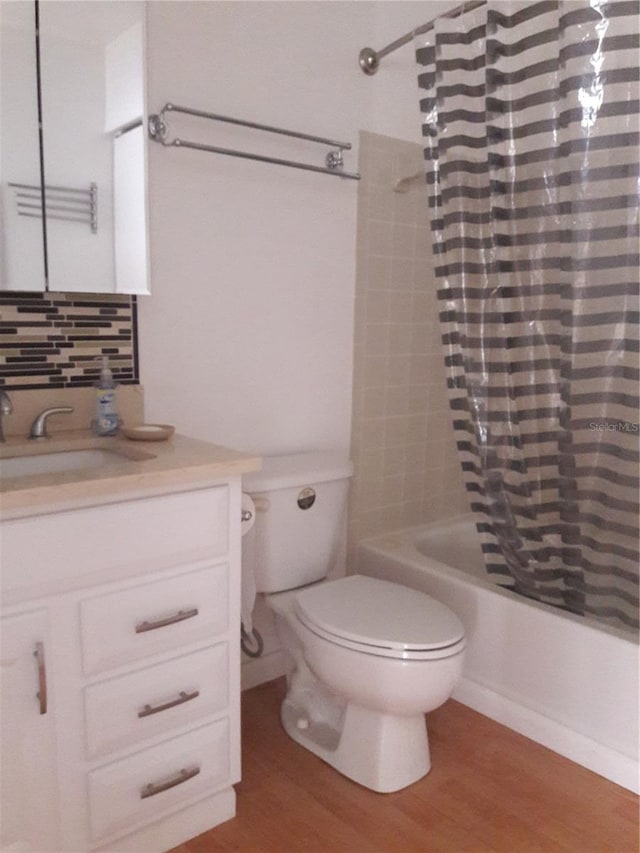 full bathroom with hardwood / wood-style floors, shower / bath combination with curtain, decorative backsplash, toilet, and vanity