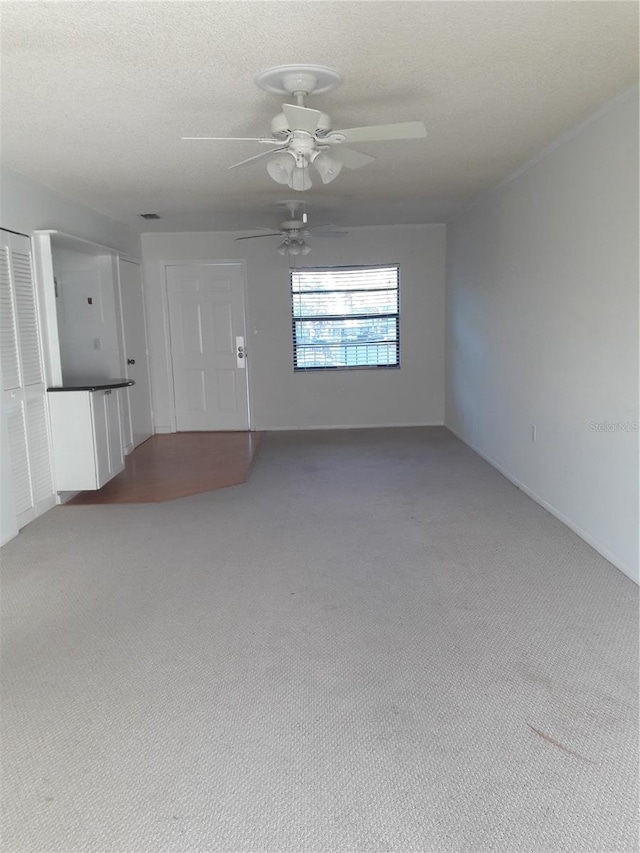 empty room with a textured ceiling, carpet, and ceiling fan