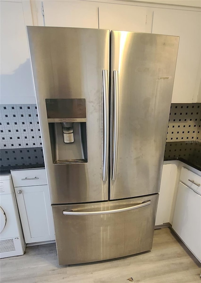 kitchen with stainless steel fridge with ice dispenser, white cabinetry, washer / clothes dryer, and light hardwood / wood-style flooring