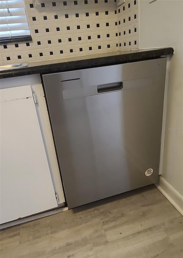 room details with stainless steel dishwasher, hardwood / wood-style flooring, and tasteful backsplash